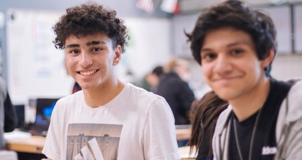 two young men in classroom smiling at camera